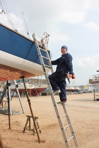 Kass climbing aboard Zest with a drill in Medina Yard